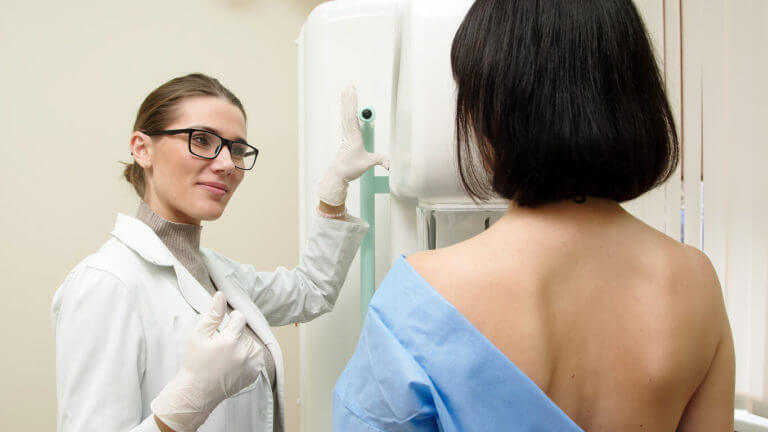 A woman undergoes a mammogram in a modern clinic under the supervision of a doctor.