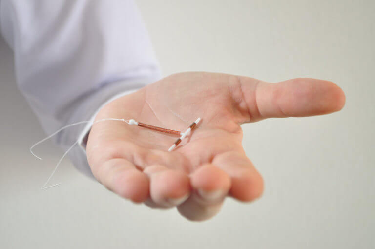 A professional holds an IUD birth control device for insertion after childbirth.
