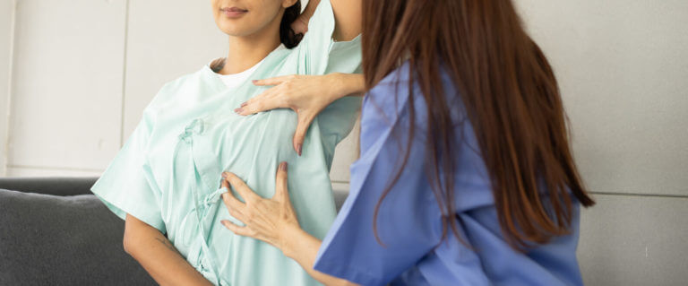 A young adult female patient is undergoing a breast cancer screening at a women's clinic with a female doctor.